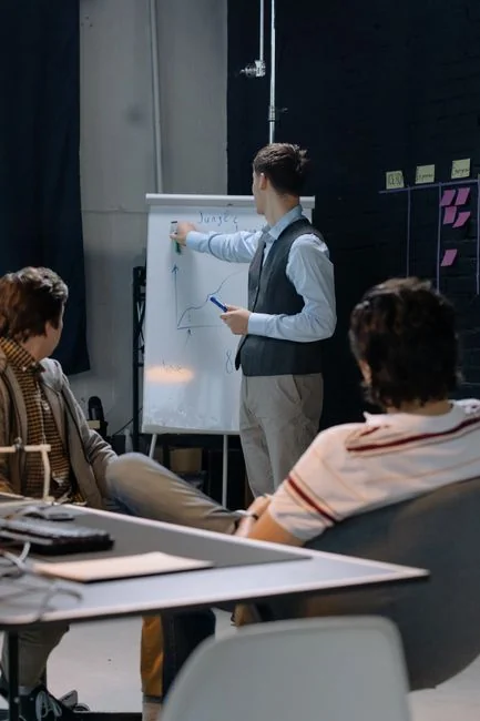 Two colleagues brainstorm ideas on a whiteboard during a creative strategy session.